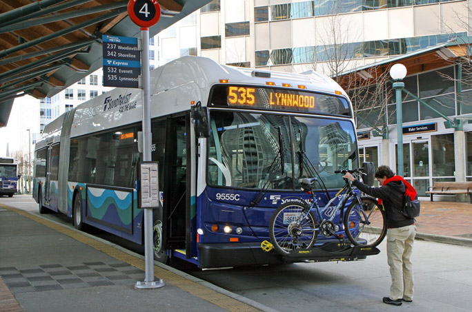 A passenger loading their bicycle onto the front of a Sound Transit Express bus before they board.